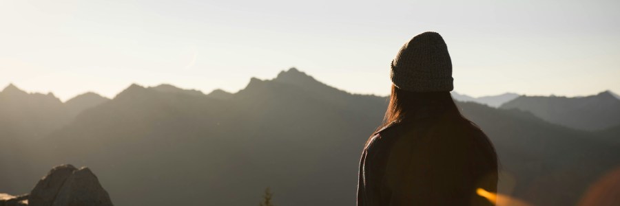 girl watches sunrise atop the mountains